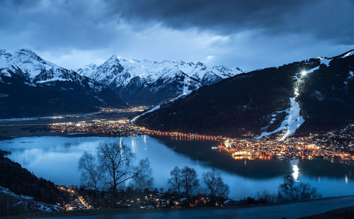 Scenic view of illuminated town by snow covered mountains