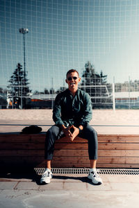 Full length portrait of young man sitting outdoors