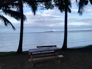 Bench on beach against sky