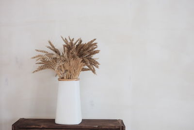 Flower vase on table against wall at home