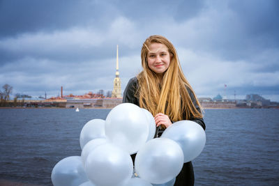 Happy cheerful girl having fun with big white latex balloons. outdoors on the
