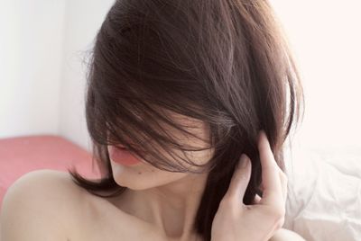 Headshot of young woman with hair across her face at home