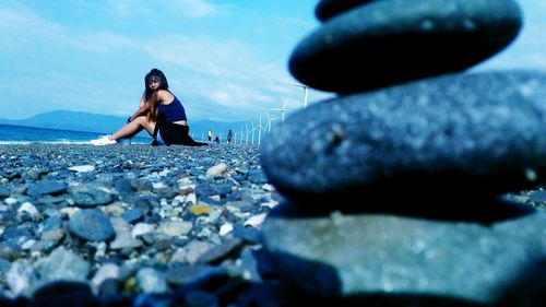 Surface level of woman sitting on stones against sky