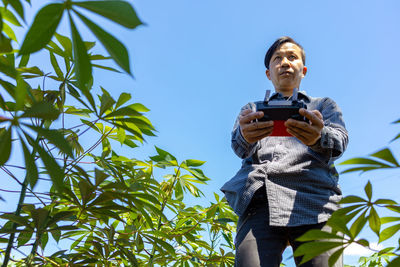 Low angle view of man using smart phone against sky