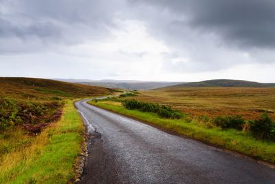 Road amidst field against sky