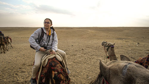 Asian woman tourist riding on camel for pyramid attraction view in egypt