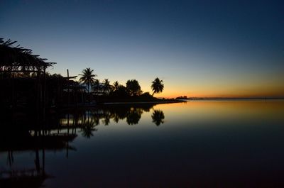 Reflection of trees in swimming pool against sky during sunset