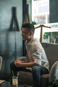 Side view of man sitting on chair