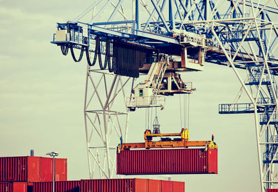 Low angle view of cargo containers and crane at harbor