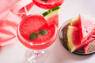 Watermelon lemonade with watermelon pieces in glasses on pink background