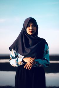 Beautiful young woman standing against sky