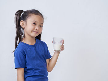 Portrait of smiling girl standing against white background
