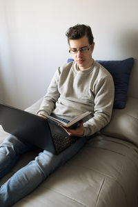 Young woman using laptop while sitting on bed at home