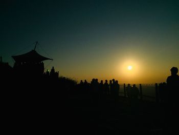 Silhouette people at temple against clear sky during sunset