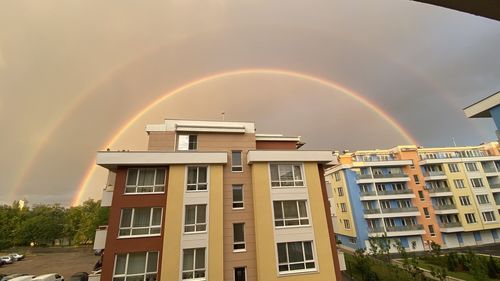 Low angle view of rainbow over buildings against sky