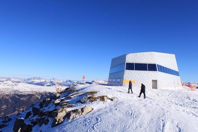 Rear view of man on snow covered landscape against clear blue sky