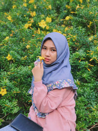 Young woman standing against plants