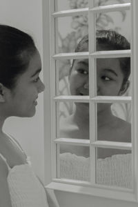 Portrait of young woman looking through glass window