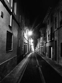 Empty road amidst buildings at night