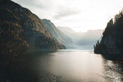 Scenic view of river by mountains against sky