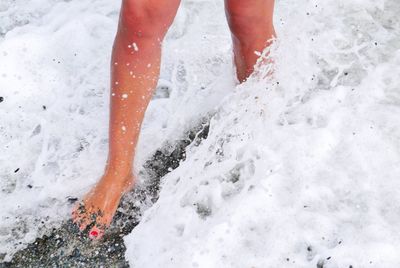 Low section of woman walking in sea