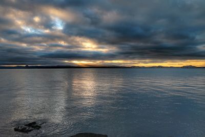 Scenic view of sea against cloudy sky during sunset