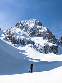 Man skiing on snowcapped mountain against sky