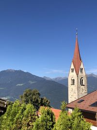 Panoramic view of building and mountains against clear blue sky