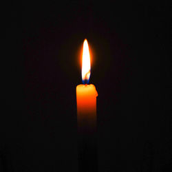 Close-up of lit candle in darkroom