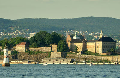 Scenic view of river by buildings against sky