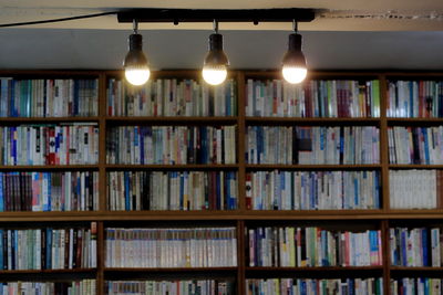 Illuminated lights with books in shelves in background