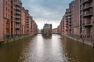 Canal amidst buildings in city against sky