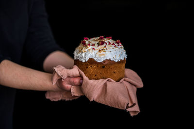 Midsection of person holding ice cream cone against black background