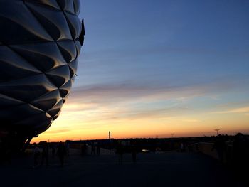 Silhouette people in city against sky during sunset