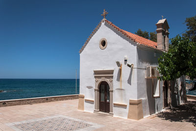 View of building by sea against clear blue sky