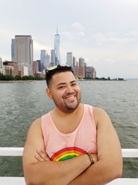 Portrait of smiling man standing against river in city