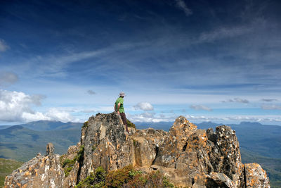 Hiker on mountain top against blue sky at hartz peak, tasmania