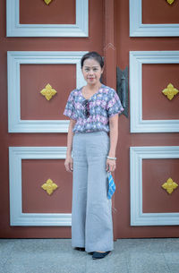 Portrait of beautiful woman standing against closed door