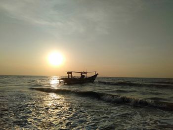 Fishing boat in sea against sky during sunset