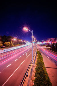 Light trails on street against sky at night