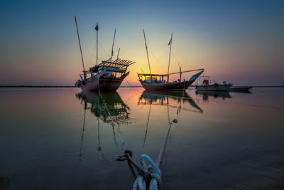 Fishing boat in sea against sky during sunset