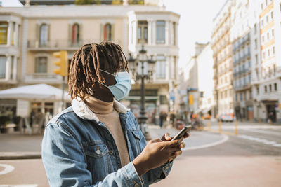 Midsection of man using mobile phone in city