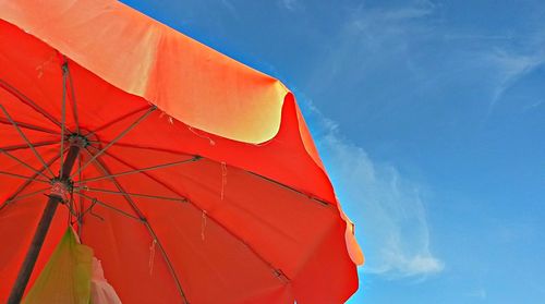 Low angle view of orange beach umbrella against sky