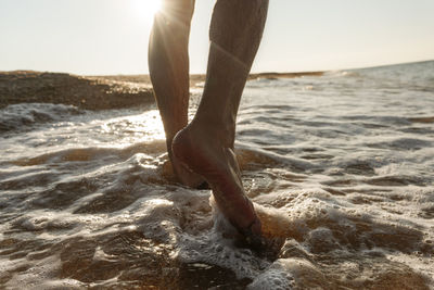 Man walking in water on shore at beach