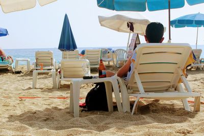 Rear view of people sitting on chair at beach