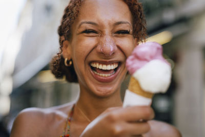 Cheerful young woman having fun with ice cream in hand