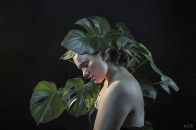 Side view of woman looking at camera over black background