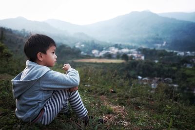 Side view of boy sitting on field