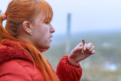 Young woman holding food while looking away