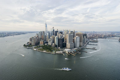 Manhattan by east river against cloudy sky